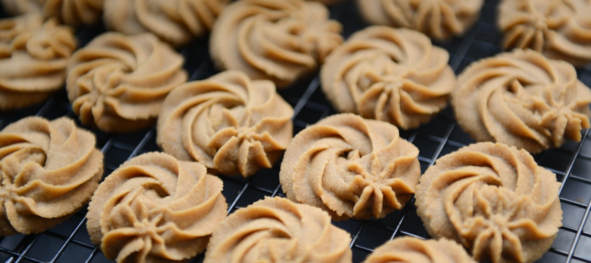 Maślane kruche ciastka o spiralnym kształcie na kratce do studzenia