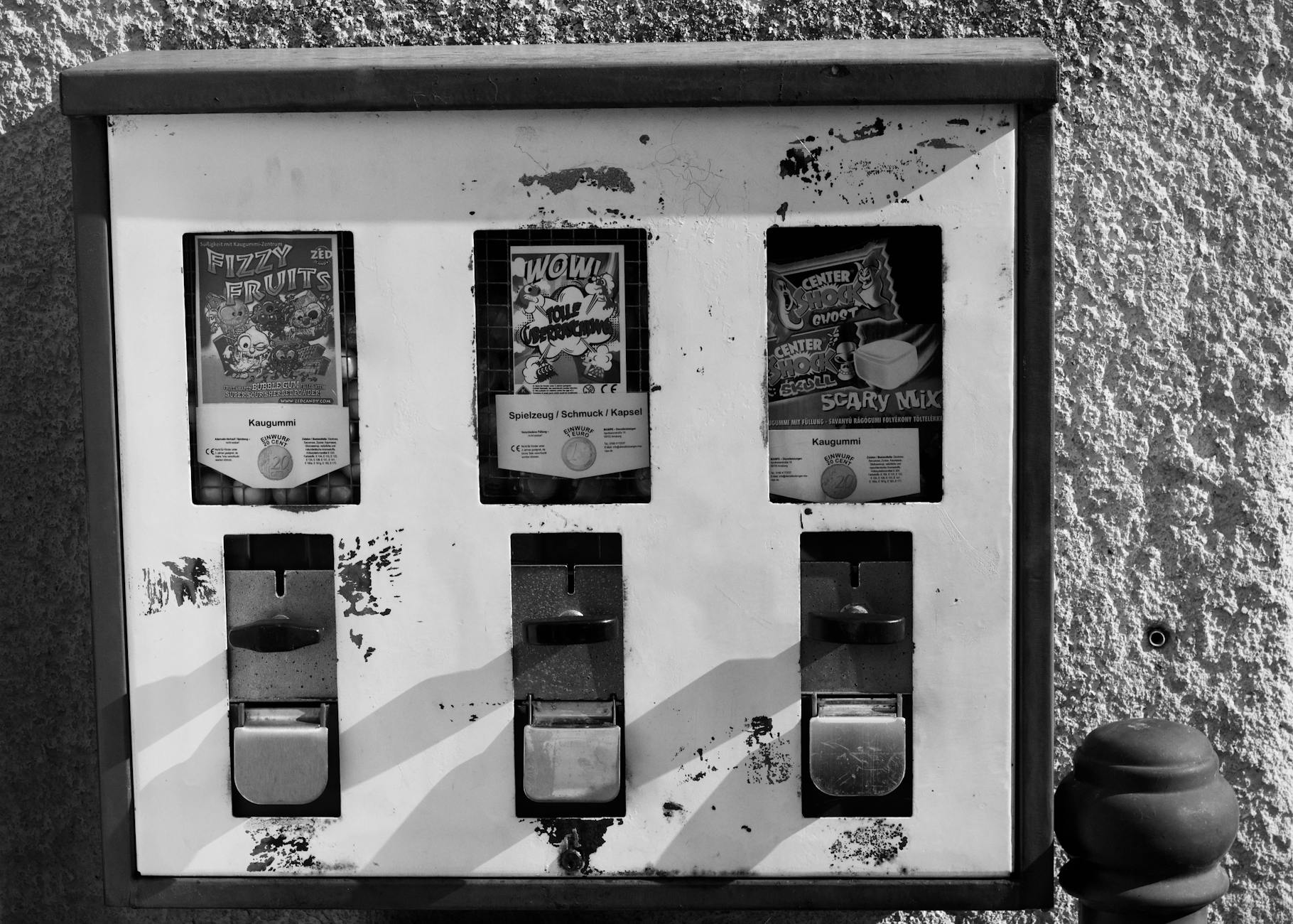 Czarno-białe zdjęcie retro automatu z gumami na zniszczonej ścianie