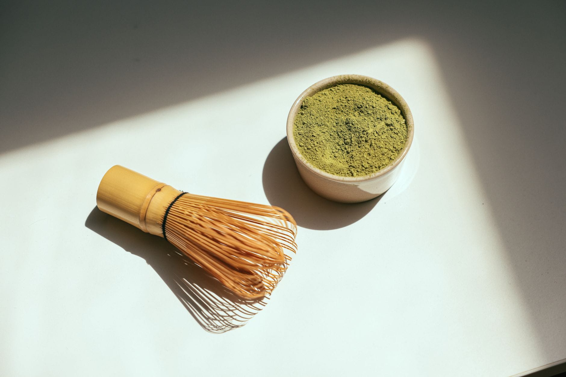 Matcha w proszku i bambusowa trzepaczka w promieniach słońca